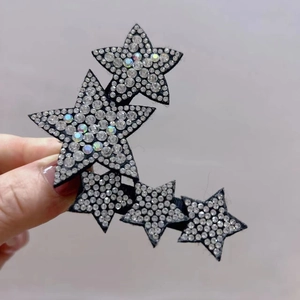 Close-up of star-shaped hair clip with sparkling white rhinestones on black fabric base