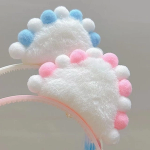Close-up of white plush cloud headband with pink and blue pom-poms for girls