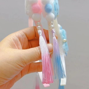 Detail of Chinese style cat ear headband with plush balls and long gradient tassels