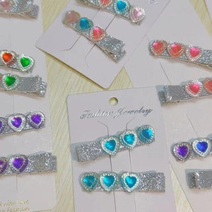 Close-up of glitter hair clips with colorful heart-shaped rhinestones on a white card
