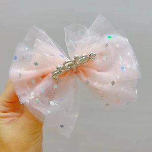 Dettaglio del fermaglio per capelli con fiocco in rete rosa, paillettes e corona