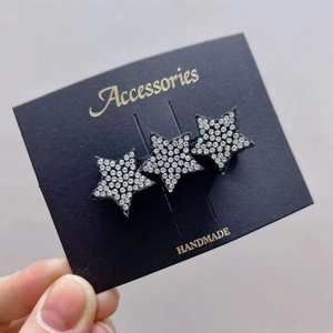 Detail of three handmade star hair accessories with clear rhinestones on display card