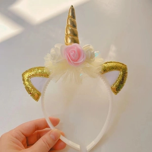 Detail of golden unicorn horn headband with pink and white roses for party performance
