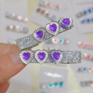 Detail view of silver glitter hair clips with three purple heart-shaped gemstones