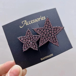 Detail of star-shaped hairpins with purple rhinestones on a handmade accessory card