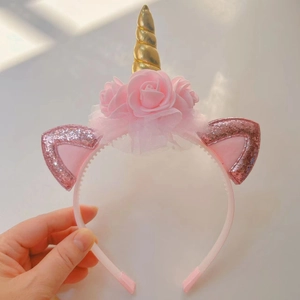 Close-up of pink unicorn headband featuring gold spiral horn and sparkly sequin ears