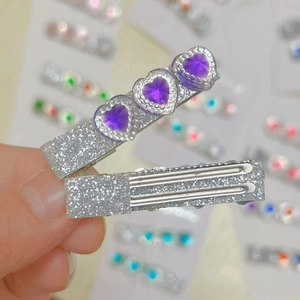 Detailed close-up of sparkling silver hair clips with three purple heart-shaped crystals