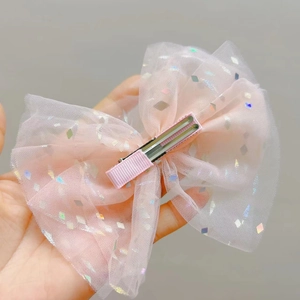 Dettaglio del fiocco in rete rosa con paillettes lucide e clip a becco d'anatra in metallo