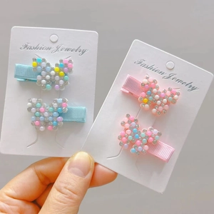 Detail view of colorful bead butterfly hair clips on white display card packaging