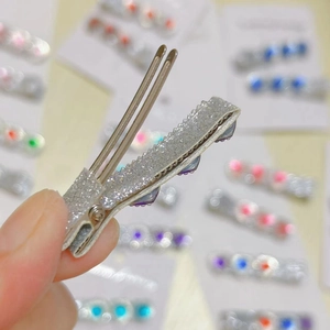 Detail of silver glitter hair clip with purple rhinestones and alligator grip design