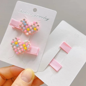 Close-up of pink heart-shaped hair clips with colorful resin beads and small rhinestones
