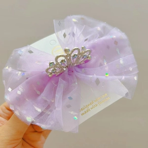 Dettaglio di un cerchietto con fiocco in tulle viola e corona di strass per bambine