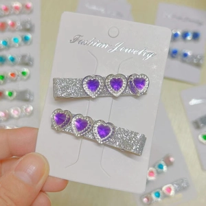 Close-up of sparkling purple heart hair clips set on a white fashion jewelry display card