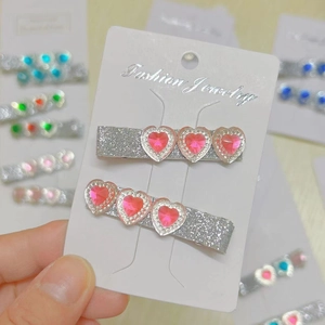 Close-up of heart hair clips with pink stones and silver glitter on branded card
