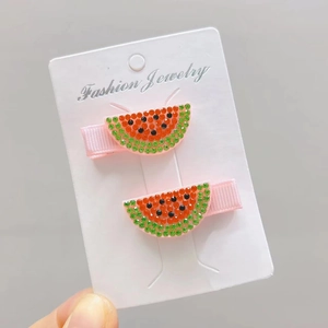 Close-up of pink watermelon hair clips with red and green sparkling rhinestones on a card