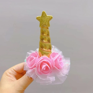 Detail of unicorn hair clip with golden horn, pink roses, and white mesh veil decoration