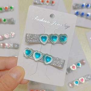 Detail of glitter silver hair clips with three sky blue heart-shaped faux gemstones