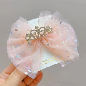 Dettaglio del cerchietto con fiocco rosa, corona di strass e paillettes colorate