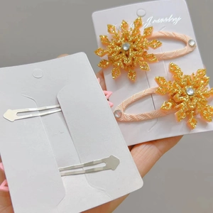 Dettaglio dei fermagli a fiocco di neve con glitter oro, strass e fibbia in metallo dorato