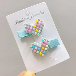 Close-up of heart hair clips with colorful pearls and rhinestones on blue ribbons