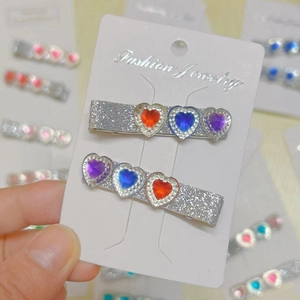 Detail of colorful heart gem hair clips with silver glitter finish and shiny rhinestones