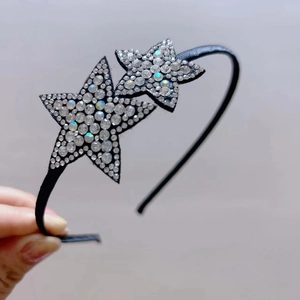 Close-up of dual rhinestone star decorations on a sleek black fabric-wrapped headband