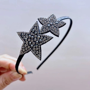 Detail showing two sparkling rhinestone stars on a slim black non-slip headband accessory