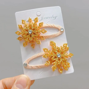 Dettaglio di fermagli per capelli a fiocco di neve glitterati con strass dorati