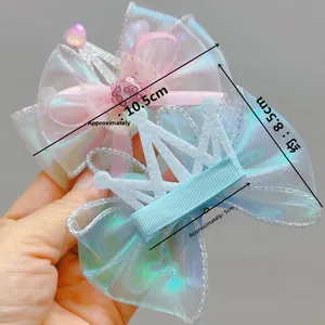 Detail view of 10.5cm iridescent organza bow hair clips with crown and heart charm