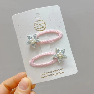 Pink star hair clips set with shimmering sequins and pearls on white card