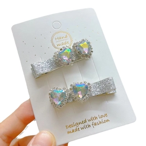 Sparkly silver hair clips set with heart-shaped colorful rhinestones on white card