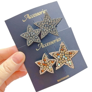 Star rhinestone hair clips in silver and orange tones on blue display card