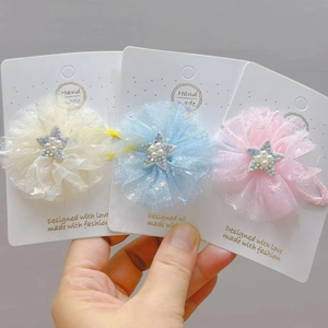 Dettaglio di tre fermagli per capelli a fiori in tulle con perle e stelle su cartoncino