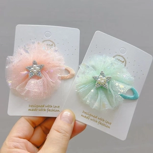 Dettaglio di due fermagli per capelli in tulle con stelle di perle rosa e menta
