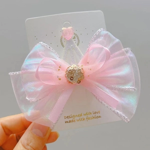 Close-up of pink iridescent organza hair bow with sequins and a heart-shaped resin detail