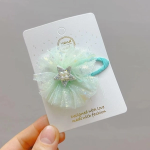 Dettaglio del fermaglio in rete verde menta con stella di perle tenuto in mano