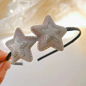 Dettaglio macro di stella in velluto grigio con glitter su cerchietto nero per capelli
