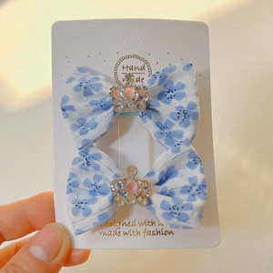 Détail de barrettes à fleurs bleues avec couronne de strass sur une carte de support
