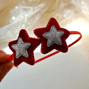 Dettaglio di un cerchietto in velluto rosso con stelle di paillettes argento per bambina