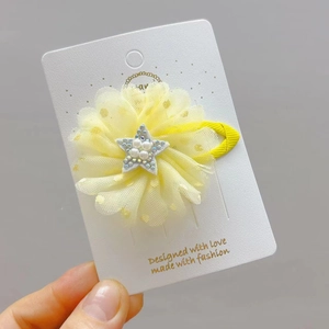 Dettaglio del fermaglio a fiore in tulle giallo con stella d'argento e perle finte