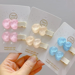 Dettaglio di fermagli per capelli a cuore in resina fatta a mano, colori rosa e azzurro