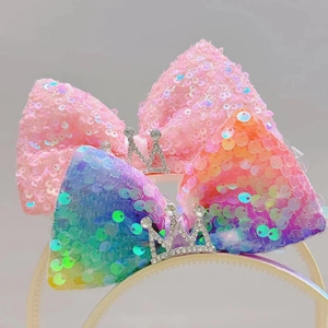 Detail van glitter pailletten strikken met strass kroon op roze en regenboog haarbanden