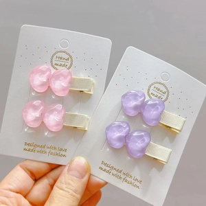 Dettaglio delle clip per capelli a cuore in resina rosa e viola con mollette a becco