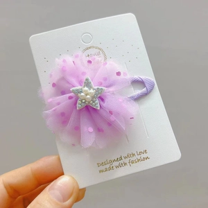 Dettaglio della clip per capelli a fiore in tulle viola con stella di perle su carta