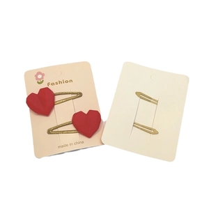 Vue détaillée de barrettes cœurs rouges avec clips dorés sur cartes fleuries de présentoir