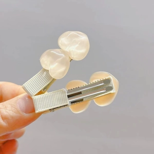 Dettaglio mollette per capelli a cuore color crema con base a becco d'anatra in metallo