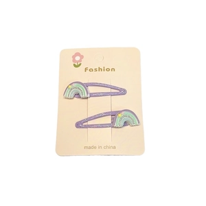 Détail de barrettes à paillettes mauves avec motifs arc-en-ciel et étoile en relief