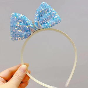Detail van de lichtblauwe paillettenstrik en zilveren kroon op de witte hoofdband