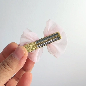 Detail einer rosa Netzbogenschleife mit glänzenden Goldpailletten und stabilem Metallclip