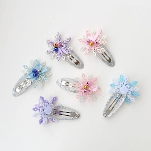 Detailed view of six glittery snowflake hair clips with bells and bows for girls